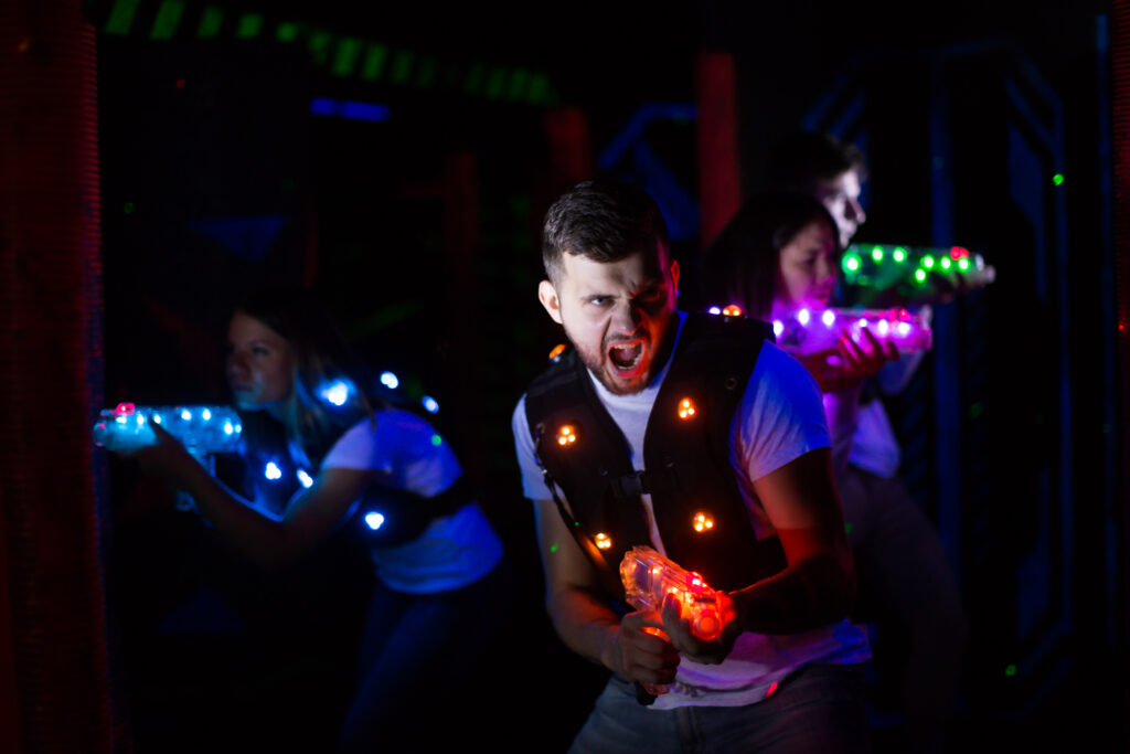 Mężczyzna celujący z broni laserowej Gra zespołowa podczas imprezy firmowej w LaserShot w Nowym Sączupodczas rozgrywki gry laser tag – idealna atrakcja na wieczór kawalerski lub męską zabawę w LaserShot, sala zabaw i park rozrywki Nowy Sącz